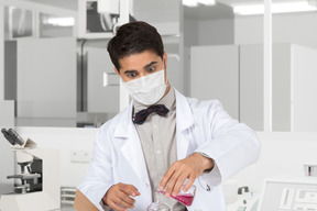 A man in a lab coat conducting experiment with a test tube