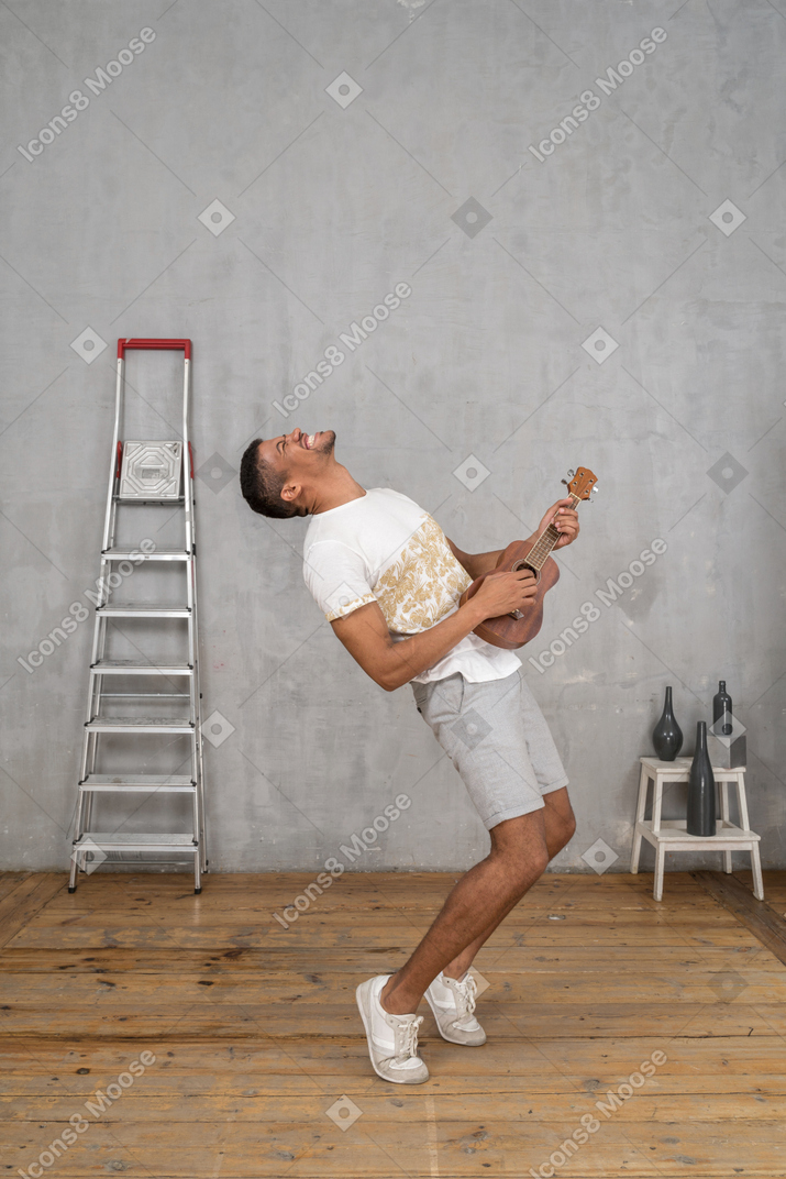 Side view of a man rocking out on his ukulele
