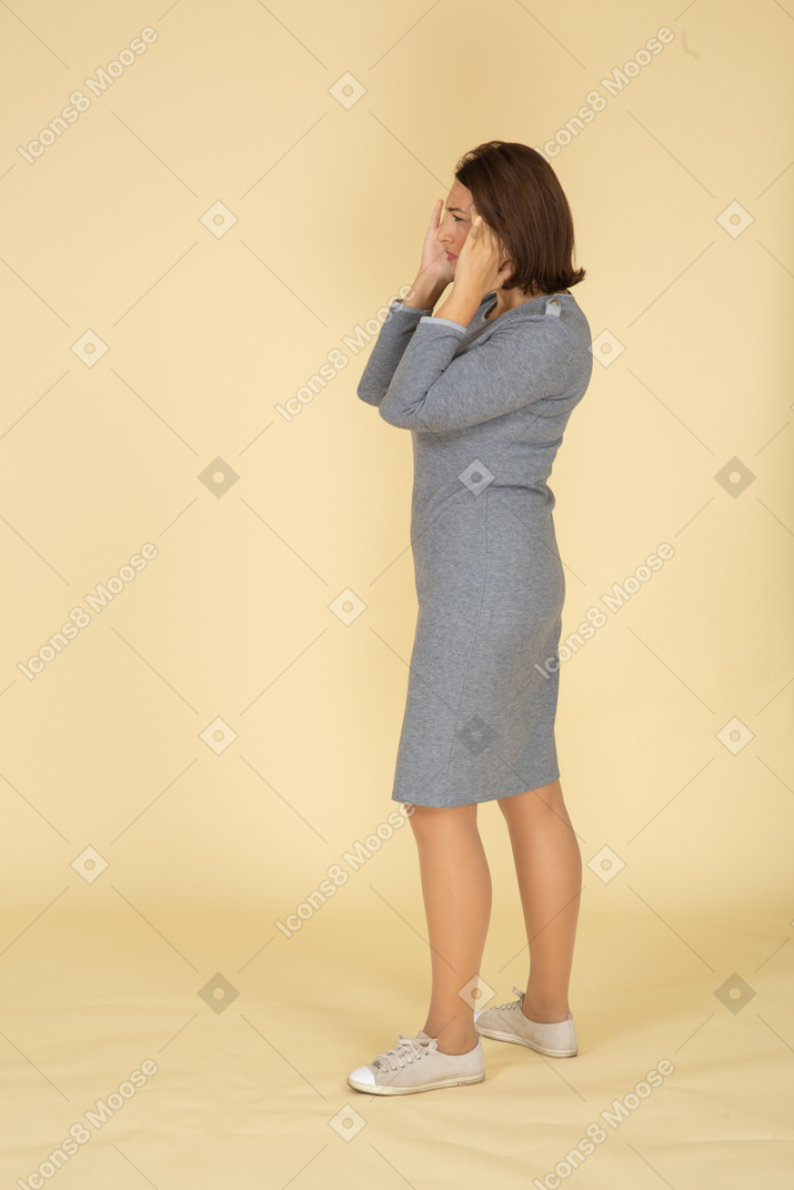 Side view of a woman in grey dress suffering from headache