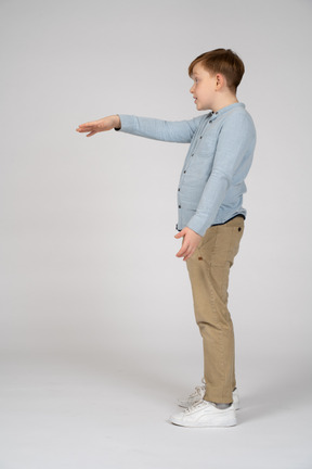  boy in blue shirt and khaki pants extending his arm forward