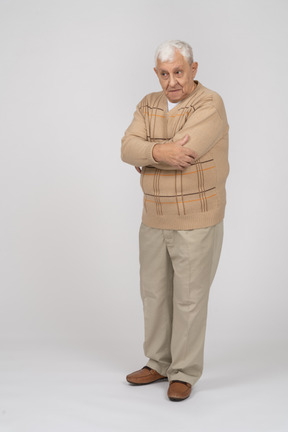 Vista frontale di un vecchio in abiti casual in piedi con le braccia incrociate