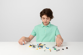 Niño con polo verde jugando con bloques de construcción
