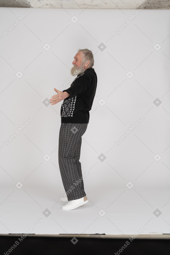 Side view of smiling elderly man standing with open arms