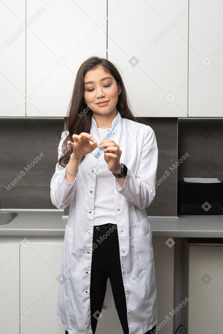 Front view of a pleased female dentist looking at the toothbrush