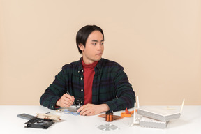 Ein asiatischer geek-typ in einem dunklen karierten hemd, der mit computerdetails arbeitet