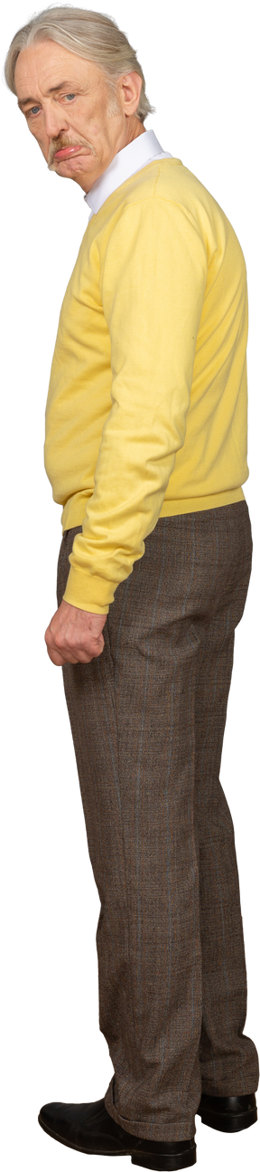 Vista lateral de um velho descontente com uma camisola amarela a olhar para a câmara