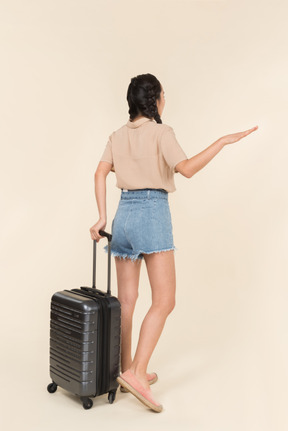 Back view of woman with luggage hailing taxi