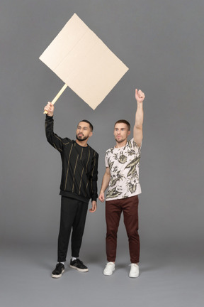 Front view of two young men waving a billboard passionately