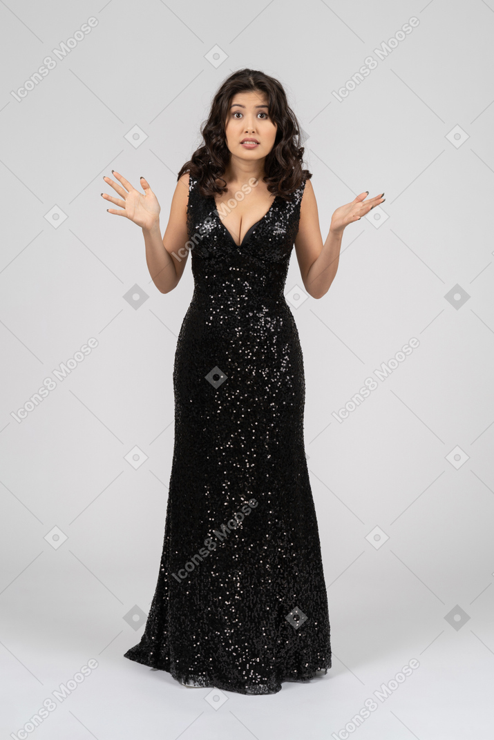 Красивая женщина в черном вечернем платье кажется озадаченной