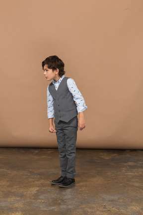 Front view of a cute boy in grey suit looking at something with interest