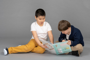 Two little friends reading book together