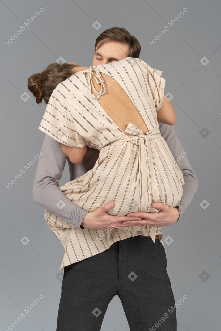Young man and woman making out with arms around each other