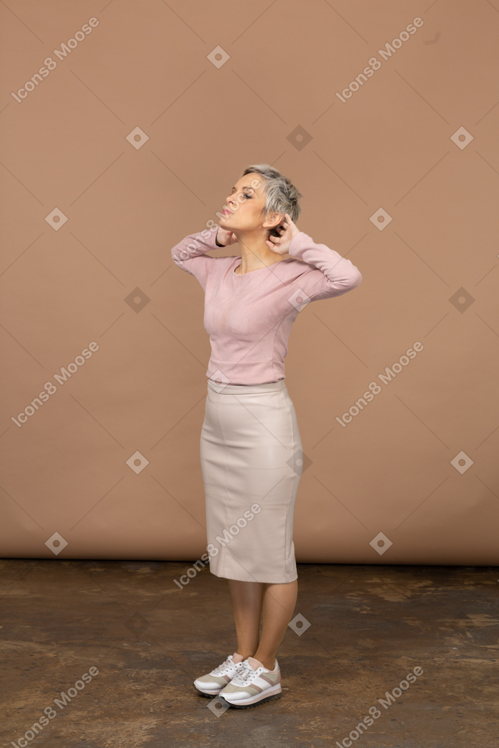 頭の後ろに手を置いて横顔に立っているカジュアルな服装の女性