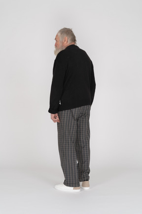 Three-quarter back view of an old man in black sweater