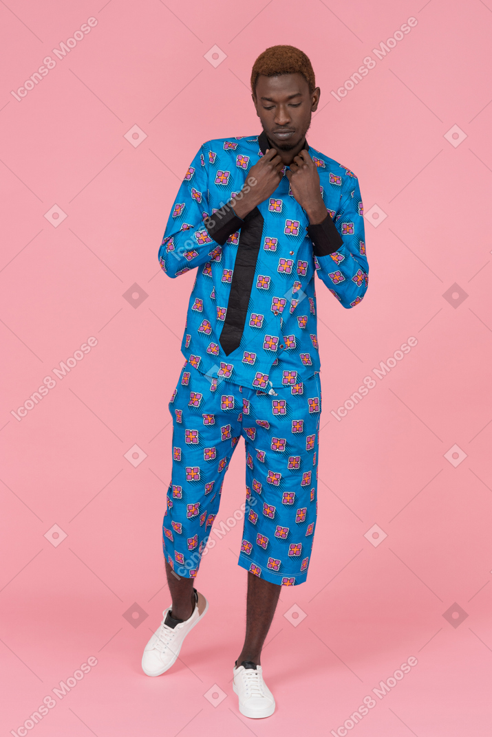Hombre negro en pijama azul de pie sobre el fondo rosa