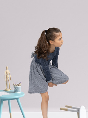 A little girl is holding her leg