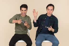 Amigos interraciales sentados en sillas y jugando videojuegos