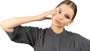 Vista frontal de uma jovem com um macacão removendo a maquiagem dos olhos