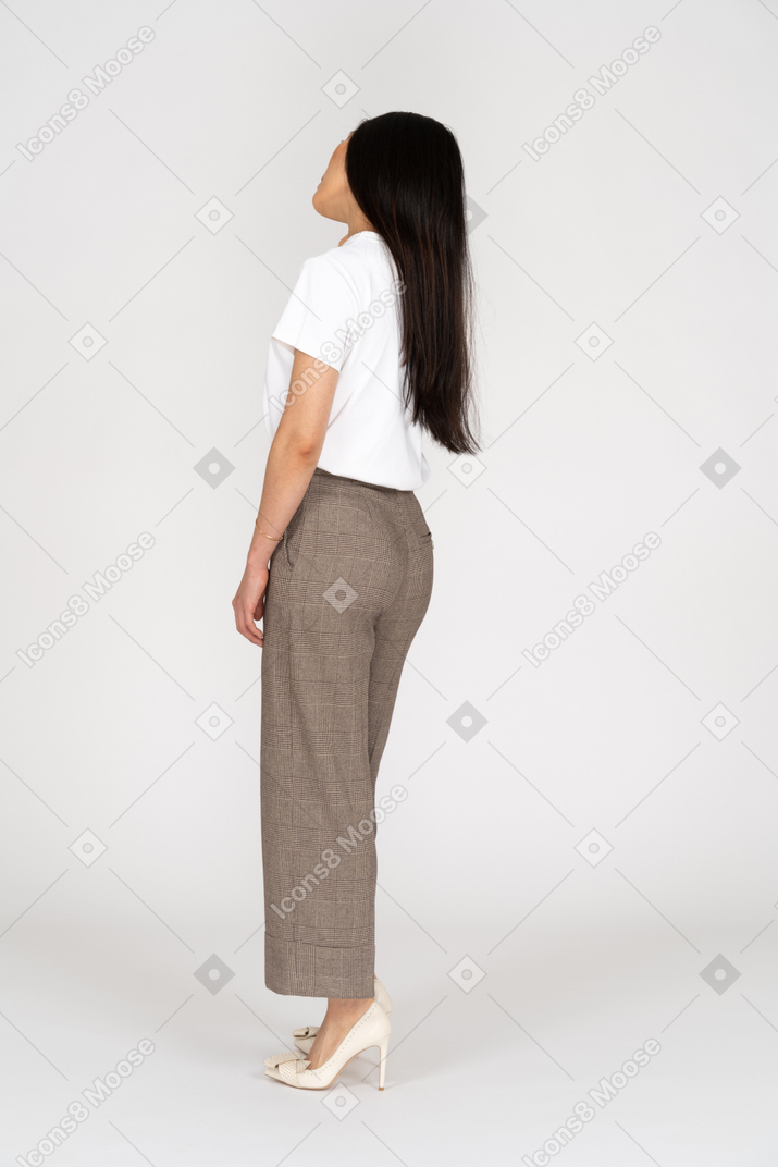 Vista posteriore di tre quarti di una giovane donna in calzoni e maglietta che si toccano il collo
