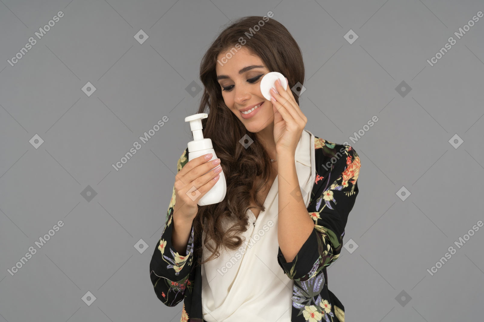 Delighted young woman applying face toner with a cotton pad