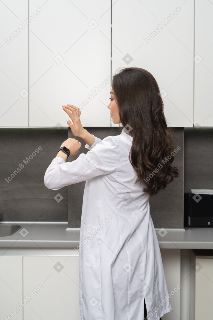 Back view of a female doctor putting a timer