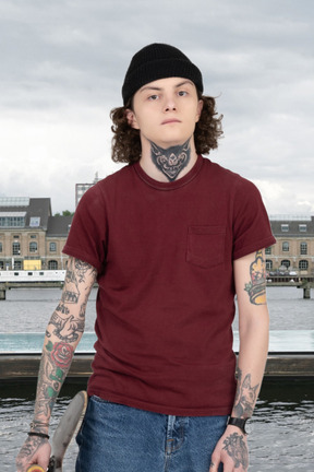 A young man with tattoos holding a skateboard