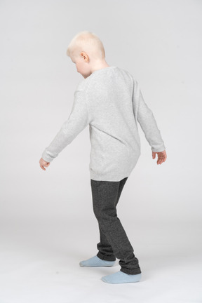 Three quarter back view of a little boy posing