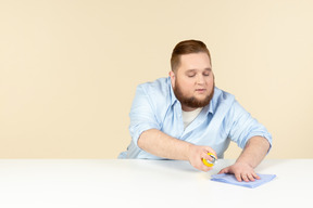 Young overweight househusband cleaning surface with spray