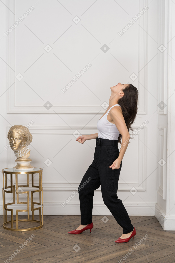 Full-length of a careful young female standing by a greek golden structure while looking up