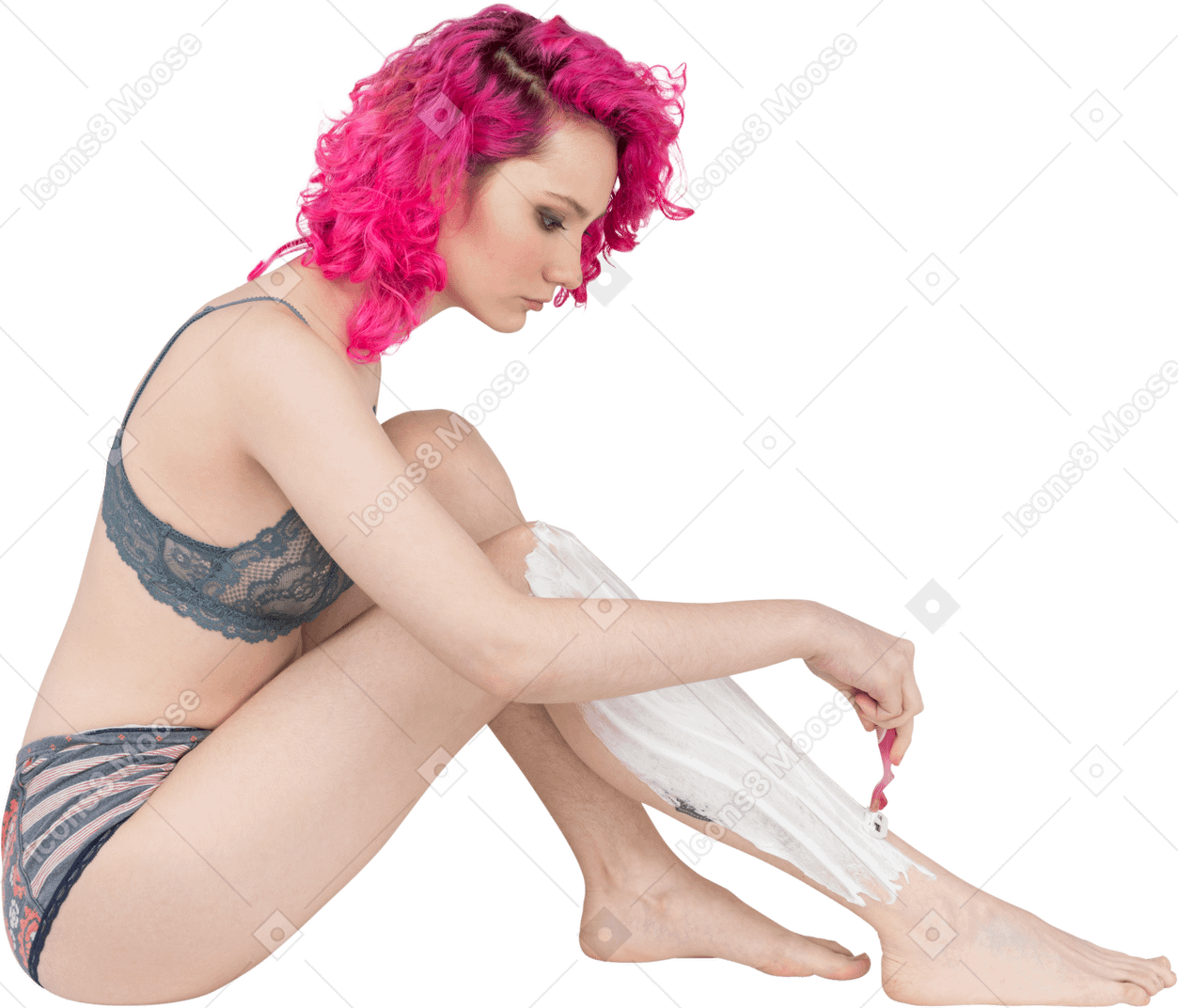 Young woman with curly pink hair shaving legs
