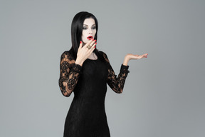 Morticia addams jadeando y cubriéndose un poco la cara con la mano