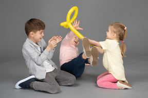 Crianças se divertindo brincando com balão amarelo