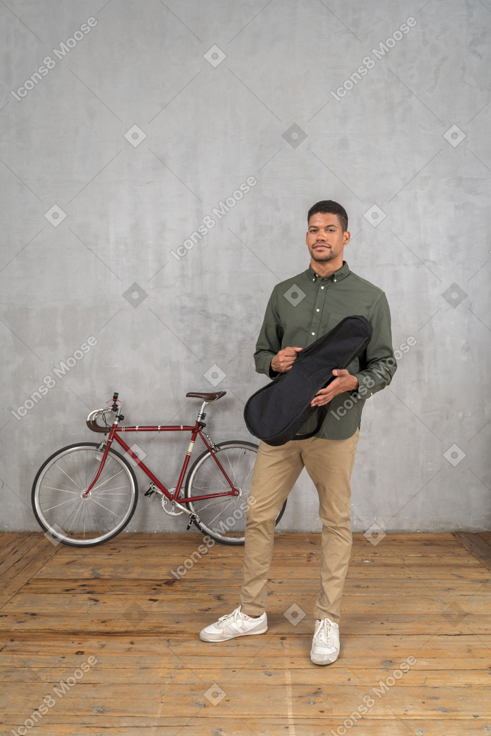 Comprimento total de um homem segurando um estojo de ukulele