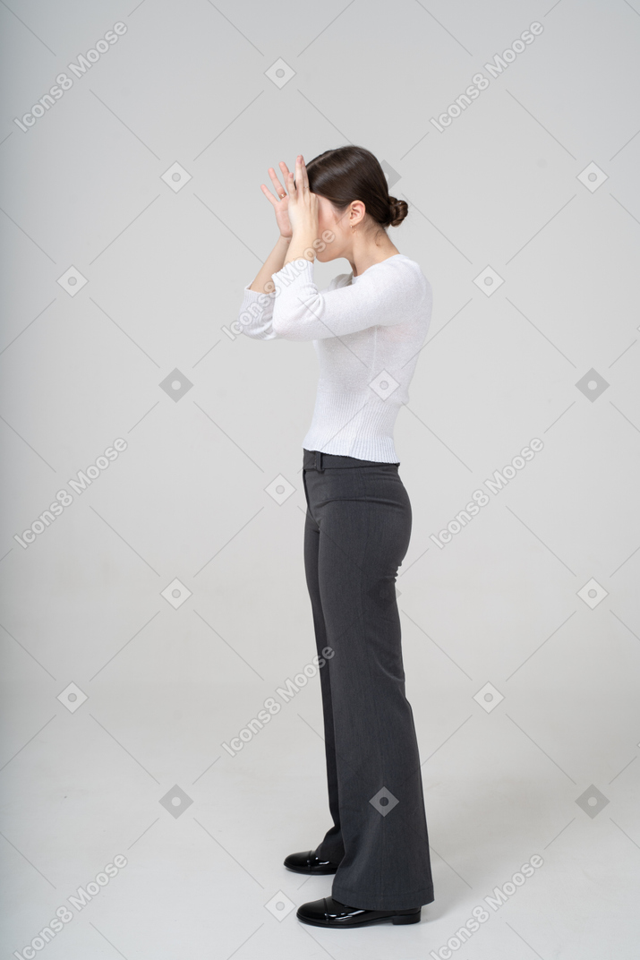 Side view of a young woman in suit looking through imaginary binoculars