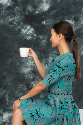 Eine frau im blauen kleid lädt zu einer tasse tee ein