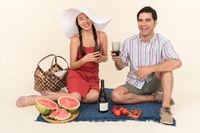 Sorrindo casal interracial fazendo piquenique e bebendo vinho