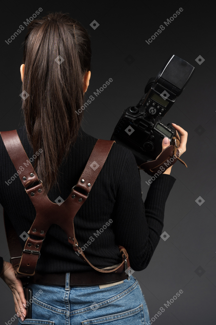 Young woman standing backwards with a camera