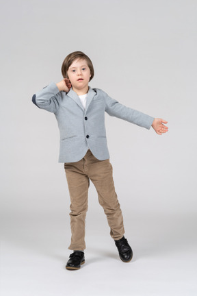 A little boy standing and outreaching his left arm