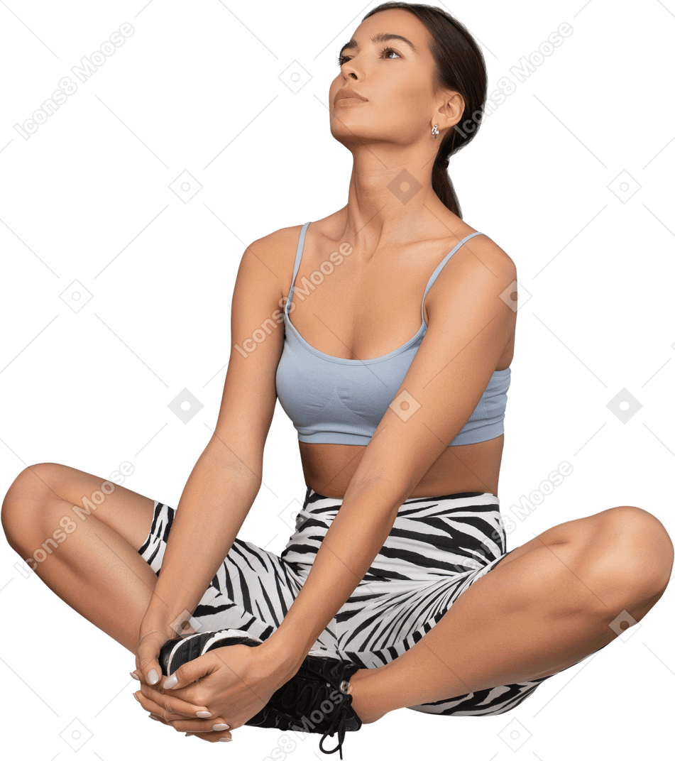 Atleta femenina mirando hacia arriba y sentada en una pose de loto