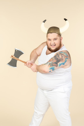 An emotional plus-sized man in white with a horned helmet on his head, holding a double-bladed axe