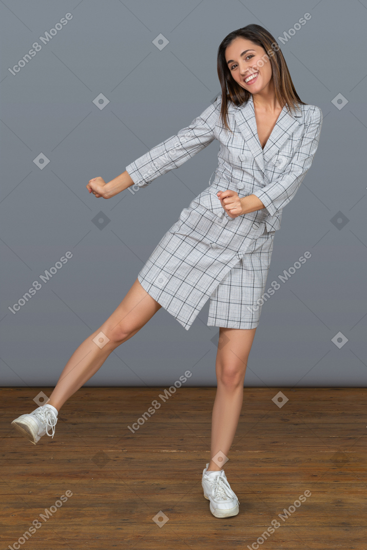 Cheerful young woman balancing on one leg and moving her hands