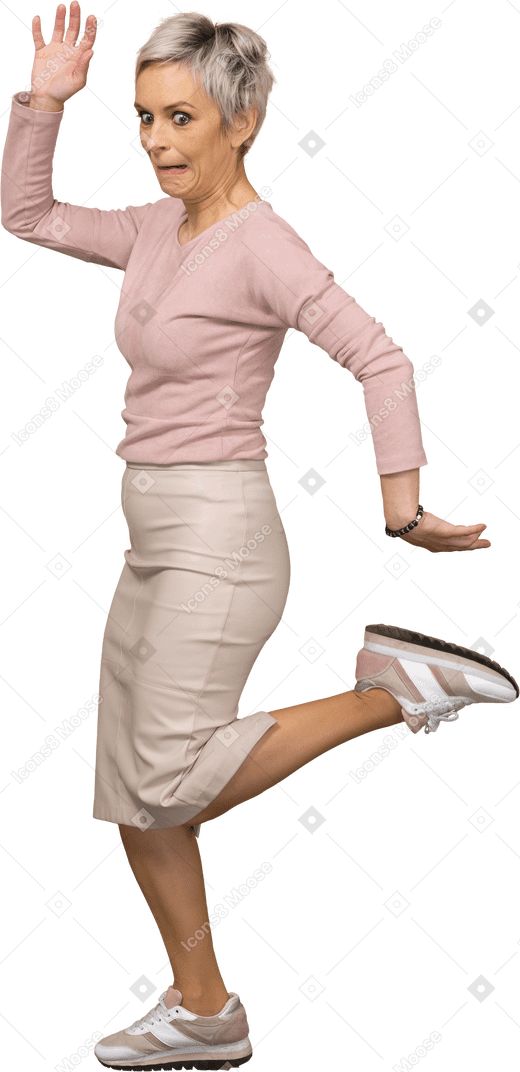 Vista laterale di una donna emotiva in abiti casual in posa su una gamba sola