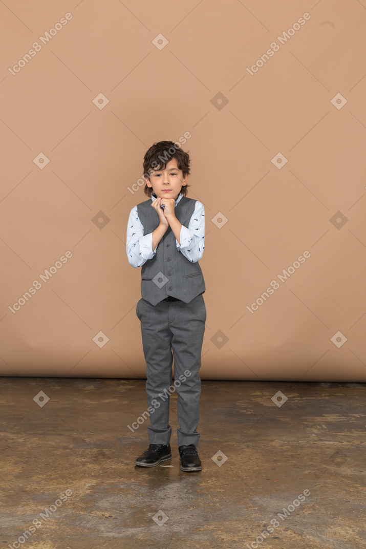 Вид спереди симпатичного мальчика в сером костюме
