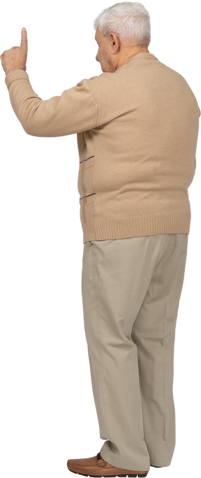 Rear view of an old man in casual clothes poinitng up with finger