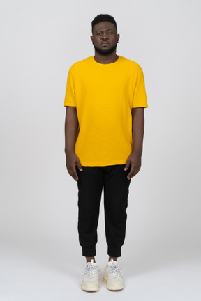 Front view of a young dark-skinned man in yellow t-shirt standing still