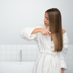 A woman brushing her long hair in a bathroom