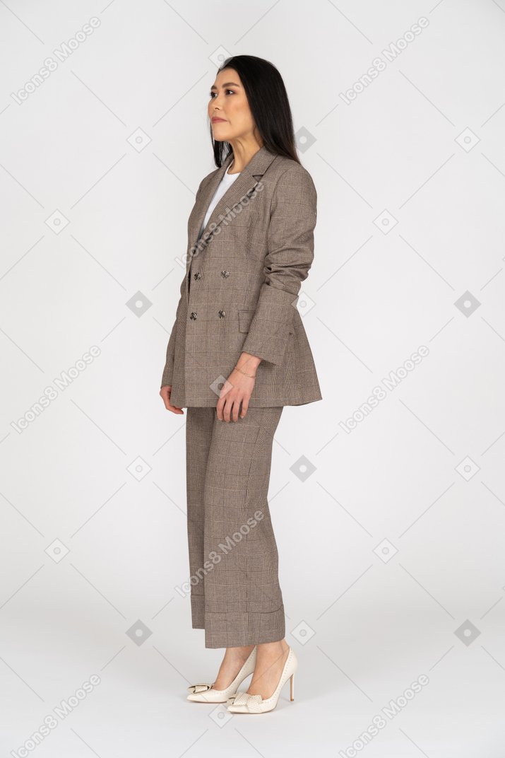 Vista de tres cuartos de una señorita en traje marrón mirando a un lado
