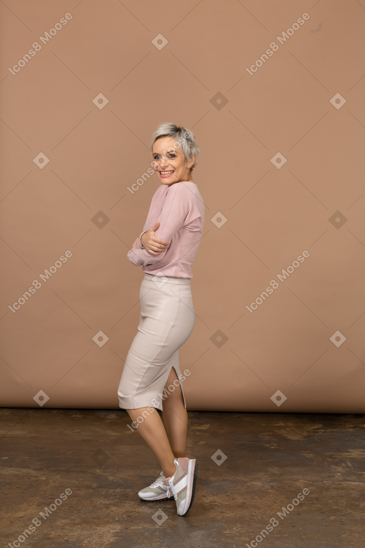Vista lateral de una mujer feliz en ropa casual mirando a la cámara
