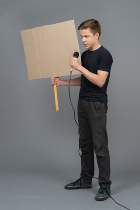 Young man speaking into a microphone and holding a poster