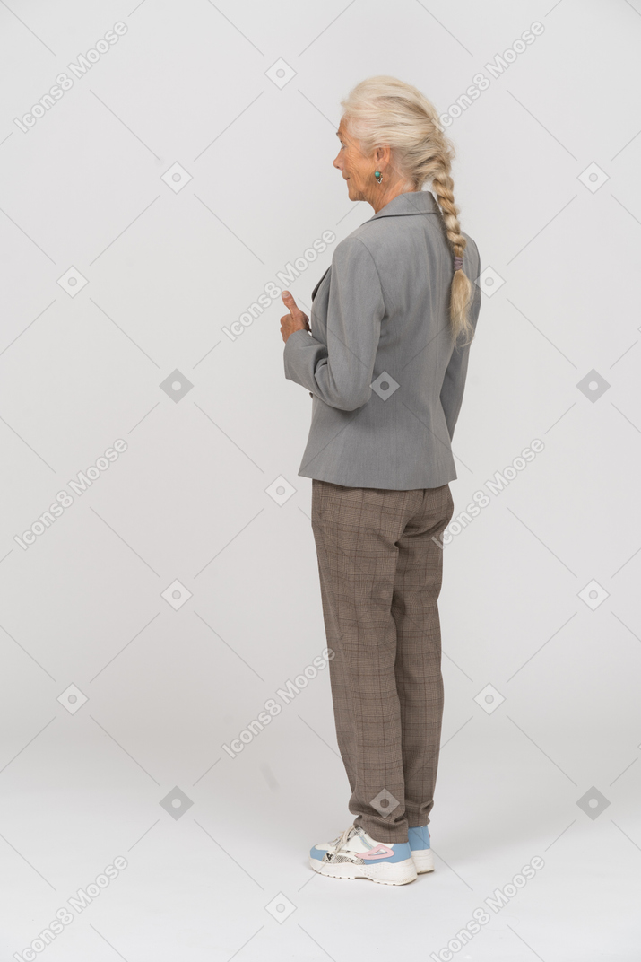 Rear view of an old lady in suit showing thumb up